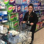 lady shopper in supermarket with full trolley kitchen rolls
